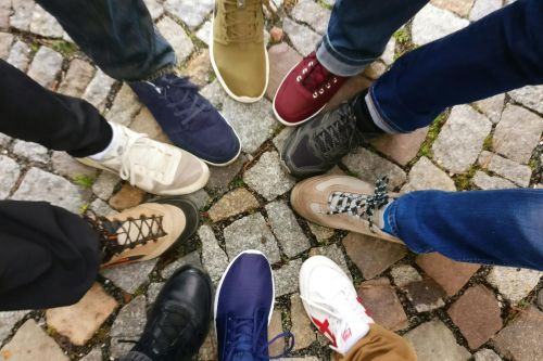 Circle of sneakers on cobblestone pavement representing diversity and urban fashion.